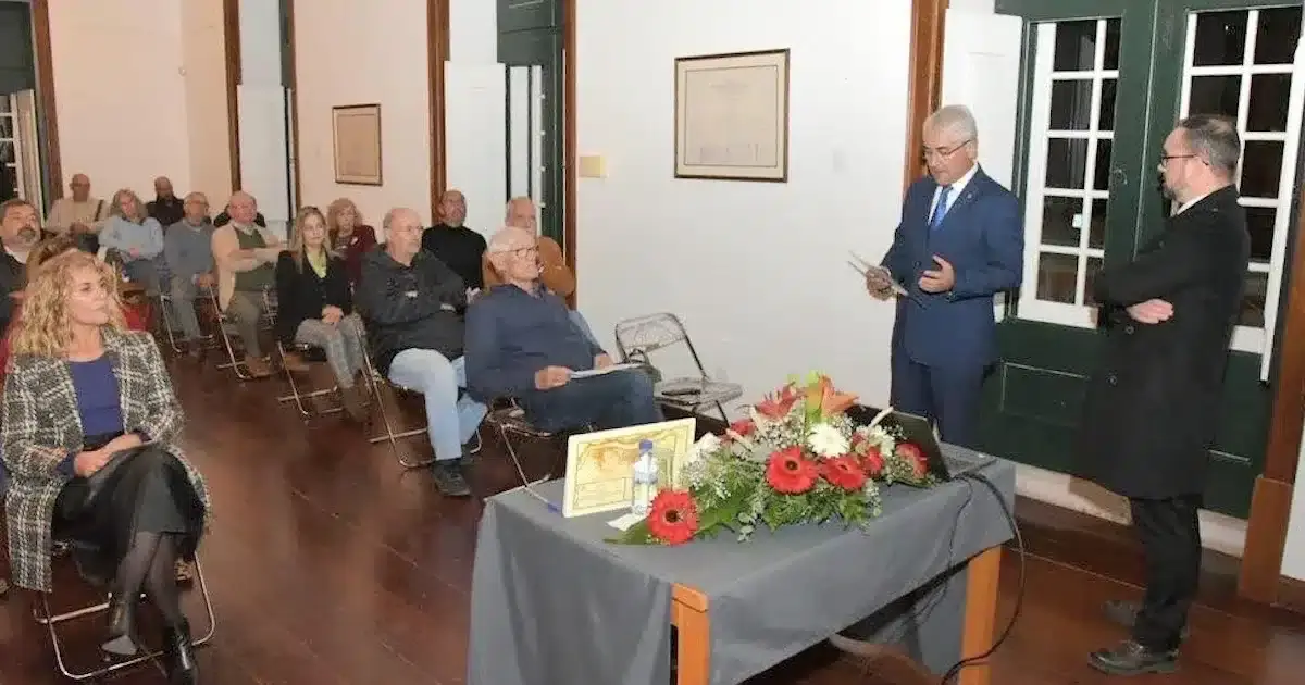 Palestra em sala com público e oradores.