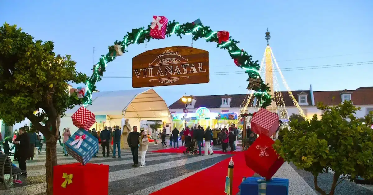 Feira de Natal em vila decorada com luzes festivas.