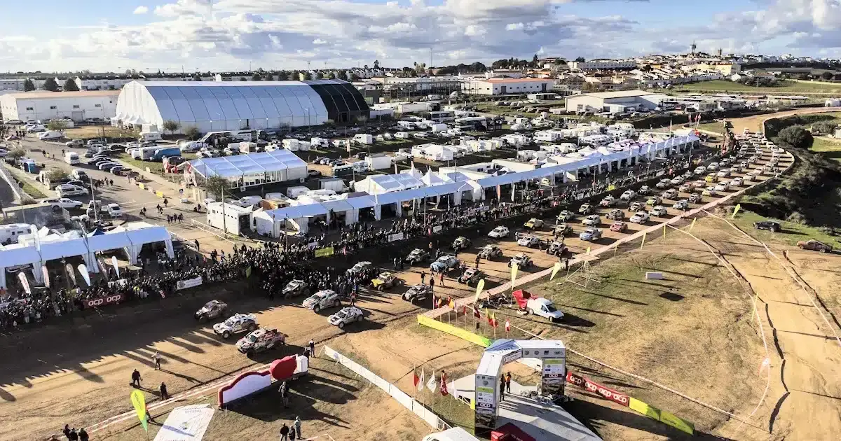 Vista aérea de feira ao ar livre com tendas e carros.