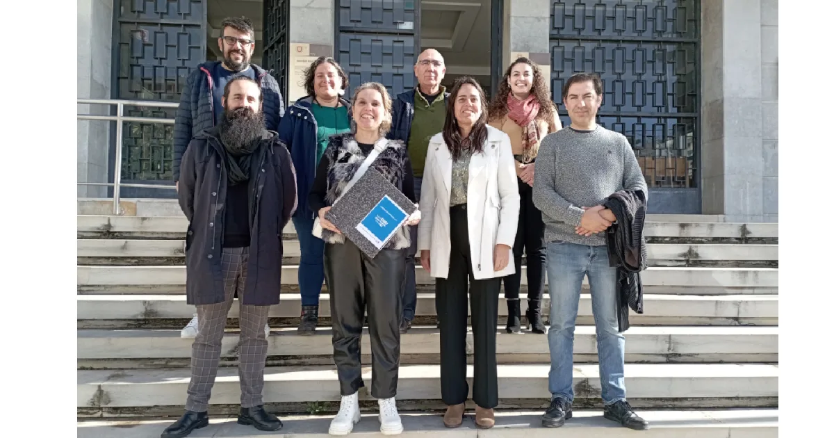 Grupo de pessoas sorridentes em frente a edifício.