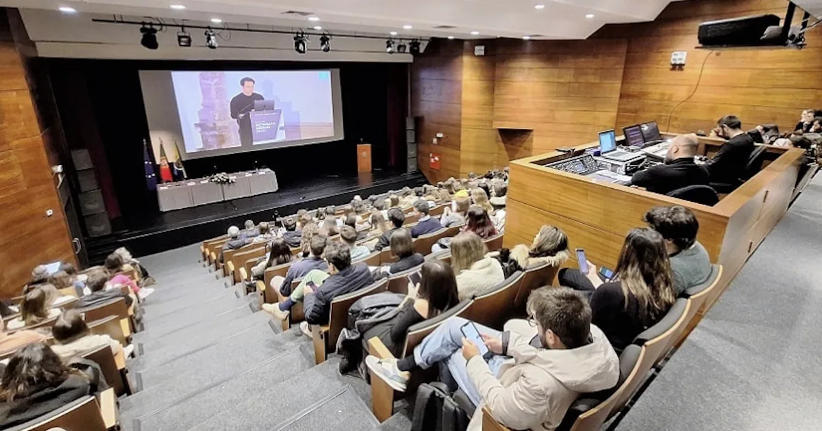 Conferência em auditório com palestrante e público atento.