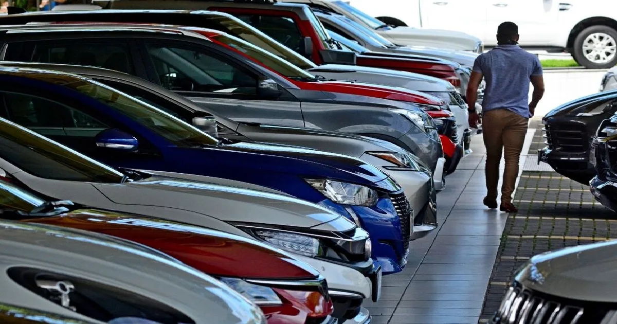 Homem caminhando entre carros estacionados.