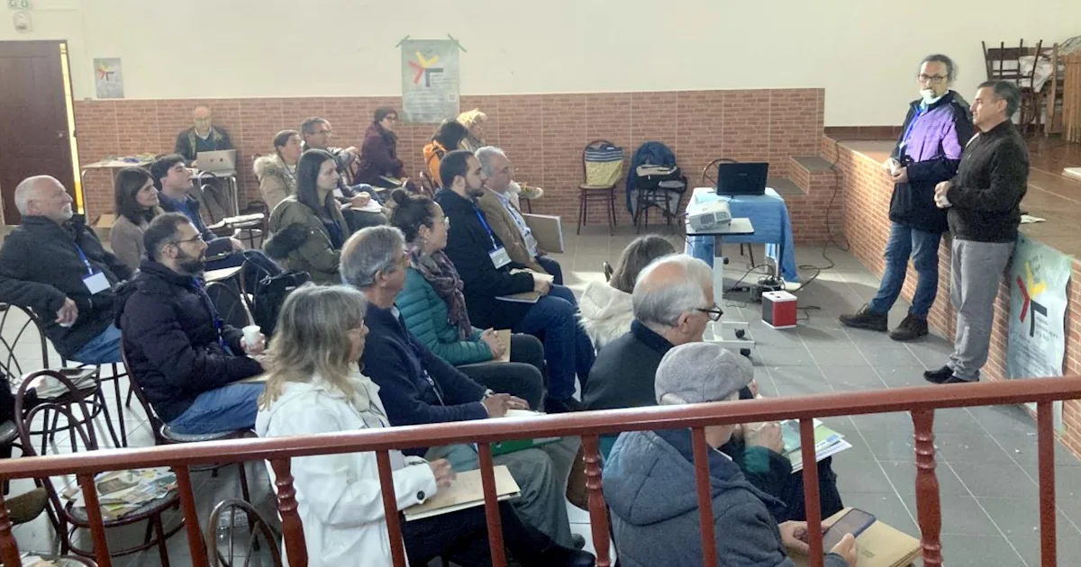 Público assistindo a uma apresentação em auditório interno.