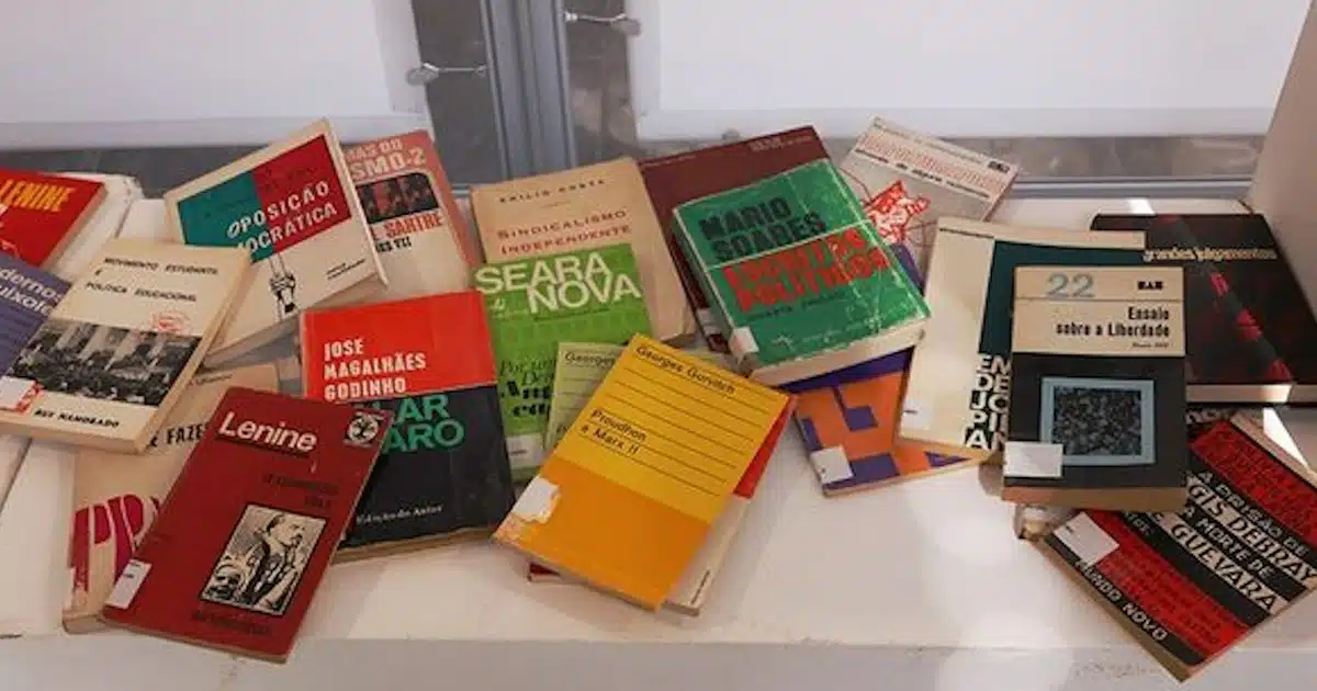 Livros antigos e políticos espalhados numa mesa.