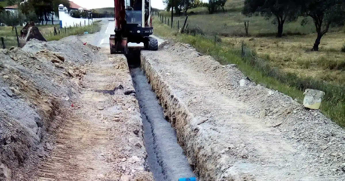 Escavadora em obra de canalização rural.